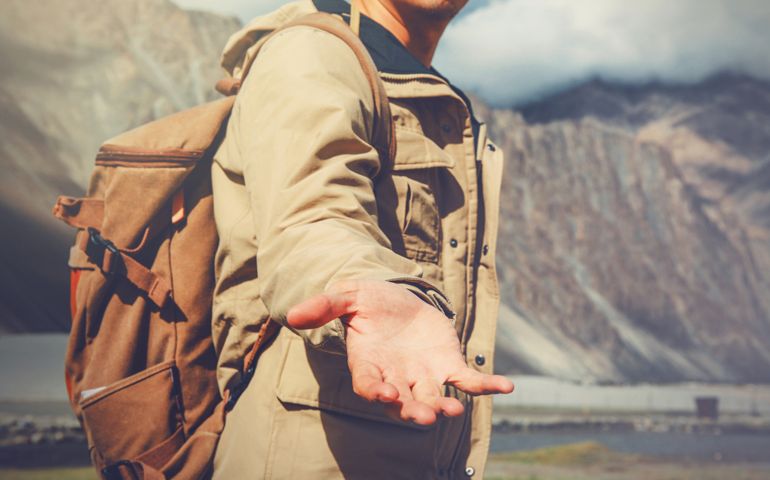 Young travel man lending a helping hand in outdoor mountain scenery.