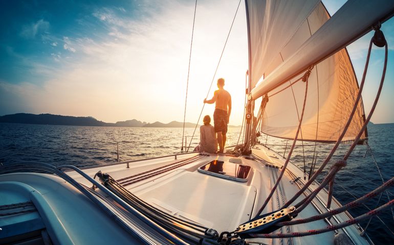 Couple enjoying sunset from the deck of the sailing boat moving in a sea