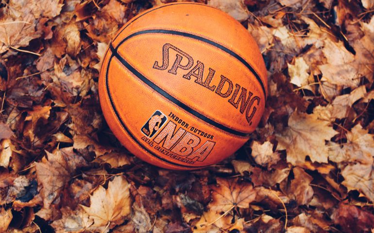 A Spalding NBA basketball resting on a bed of dried autumn leaves, symbolizing the changing seasons and the timeless love for the game.