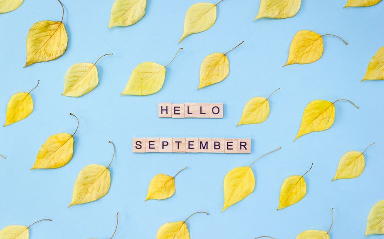 Rows of yellow autumn leaves on a blue background surround scrabble tiles spelling “Hello September”—a nod to the quiet shifts and historic moments that define this in-between month.
